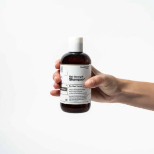 Scandinavian Biolabs Šampon za rast kose Žene 250 ml - bočica šampona u ruci žene.